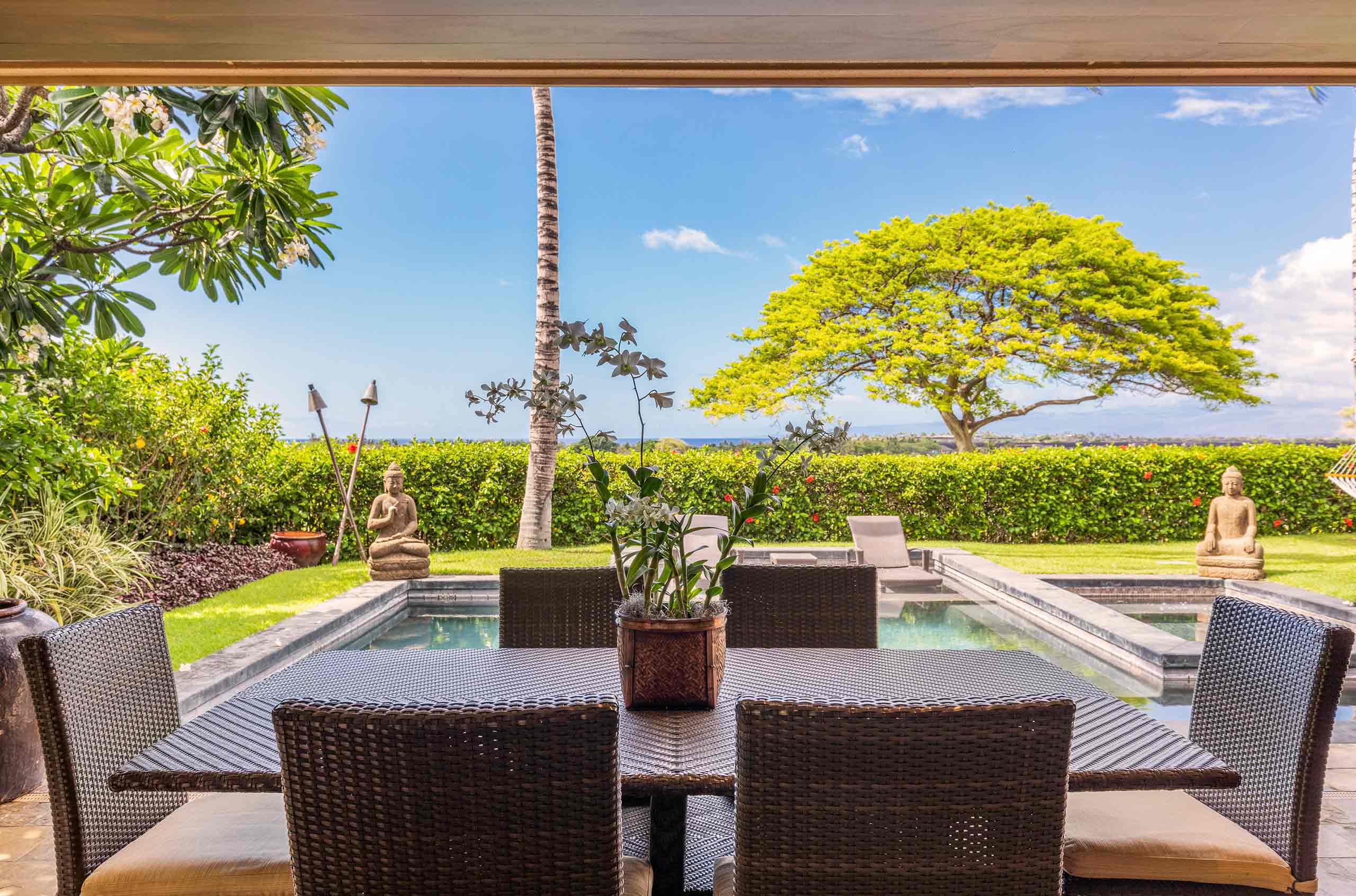 Al fresco dining in a Big Island Cuvée luxury villa with sweeping ocean views, outdoor lounge, and private natural pool and spa.