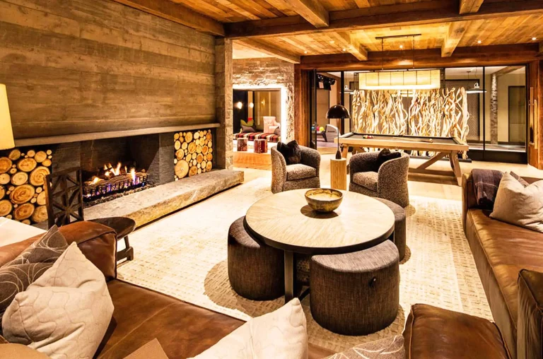 Luxurious living room with a fireplace, plush seating, and a pool table in a stylish villa.