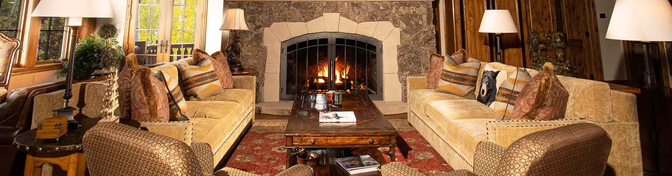 Cozy living room with plush sofas, a wooden coffee table, and a stone fireplace.