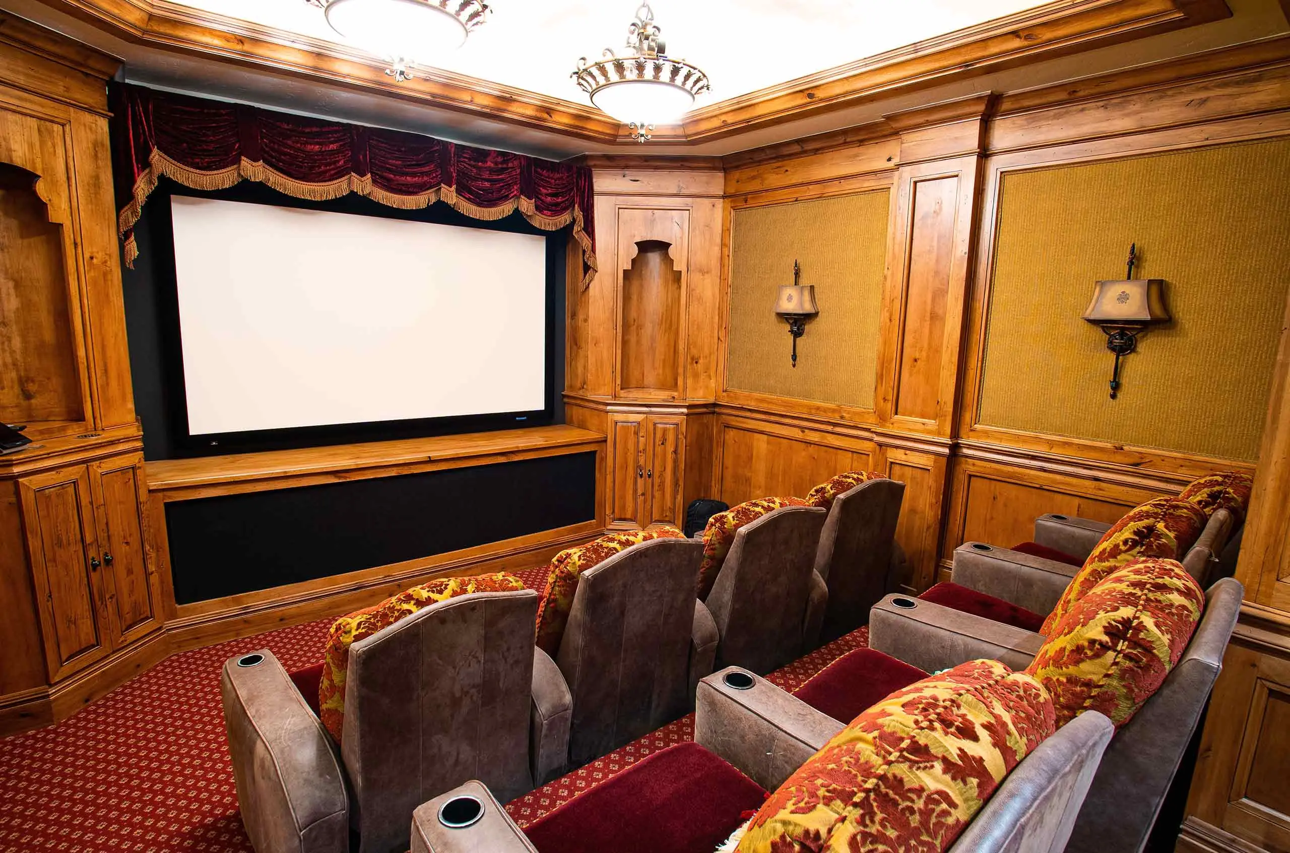 Home theater room with luxurious seating and wooden paneled walls.