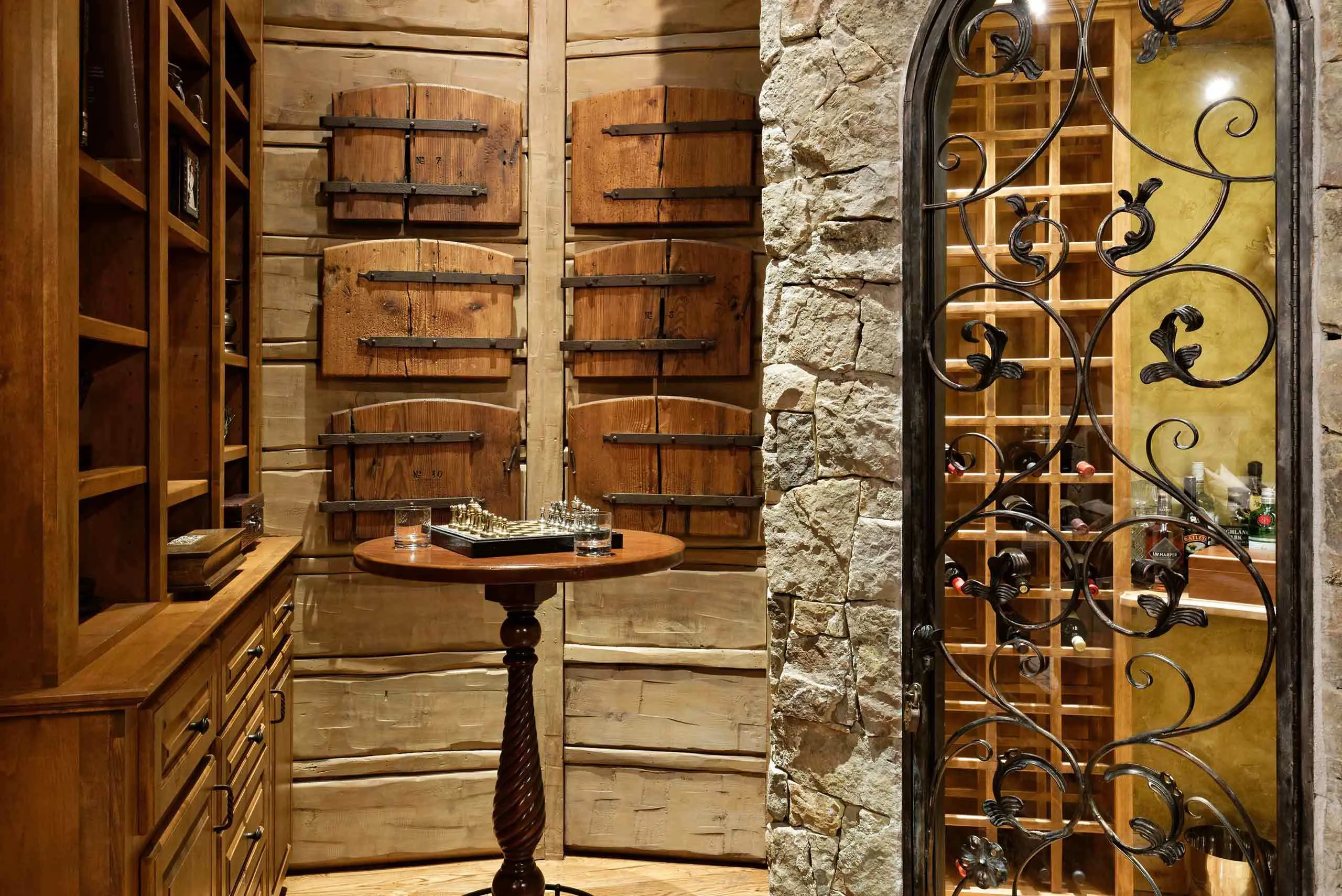 Rustic wine cellar with wooden shelves and a wrought iron gate.