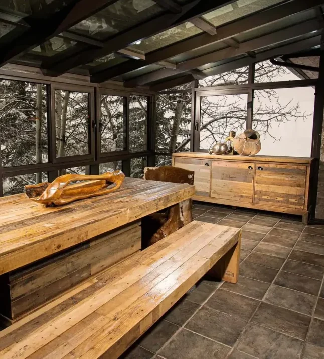 Rustic wooden dining area with large windows and natural decor in a luxury villa.