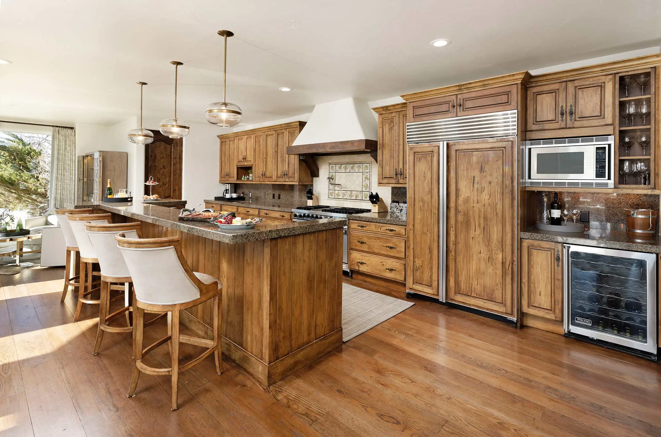 Luxurious kitchen with wooden cabinets, center island, and bar stools in a vacation rental villa.