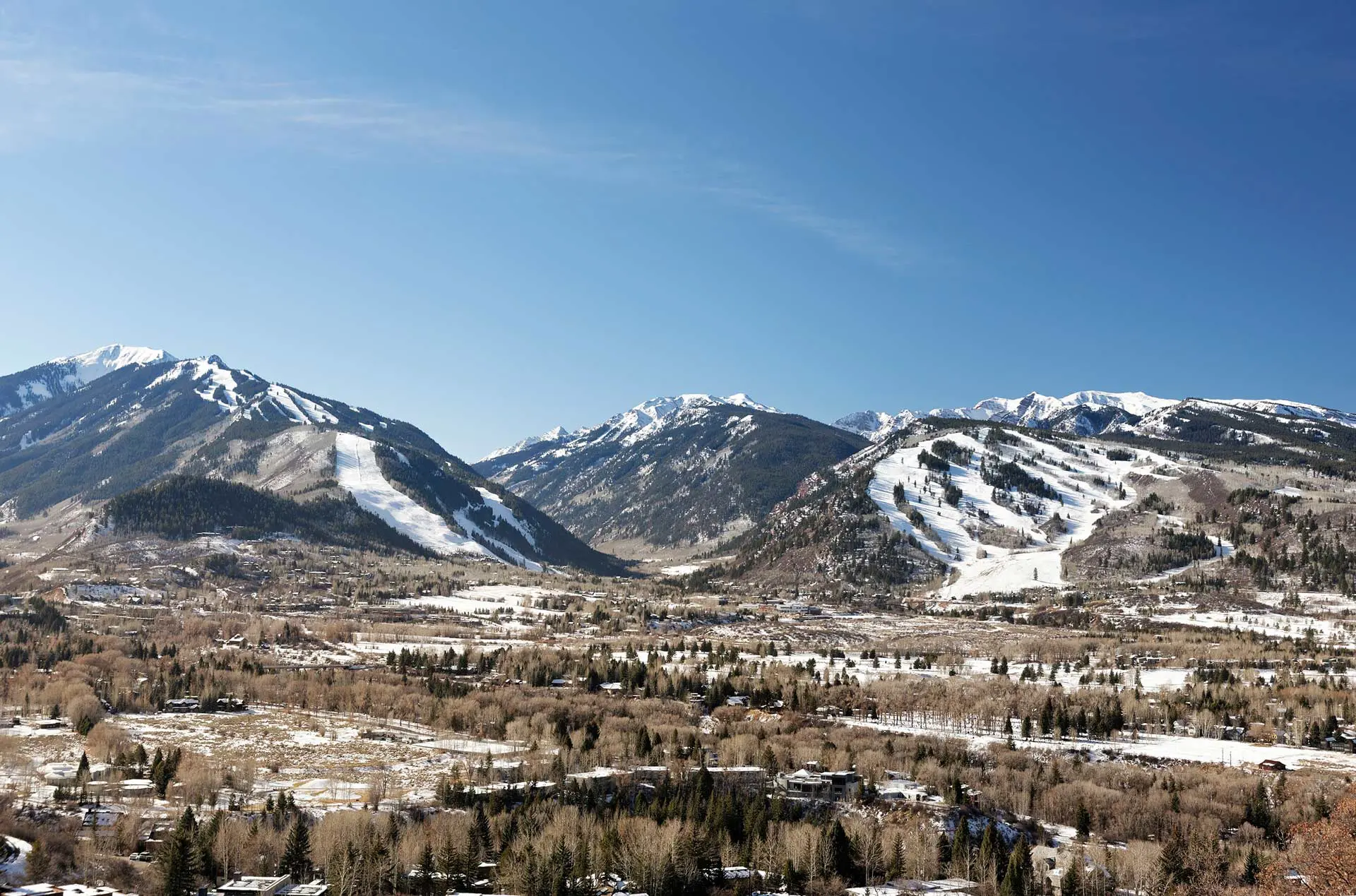 Scenic view of snow-covered mountains and a valley under a clear blue sky.