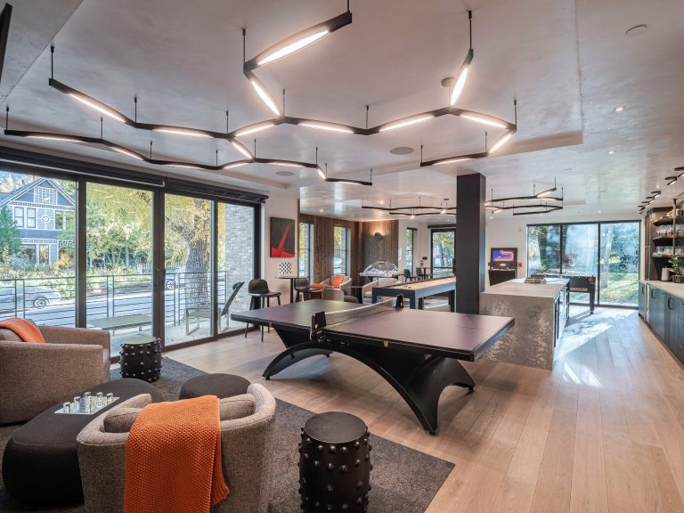 Luxurious villa interior with modern furnishings, a ping pong table, stylish lighting, large windows, and outdoor views.
