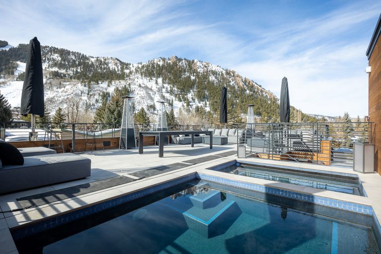 Luxury villa patio with pool, outdoor seating, and snow-covered mountain view in Aspen, Colorado.