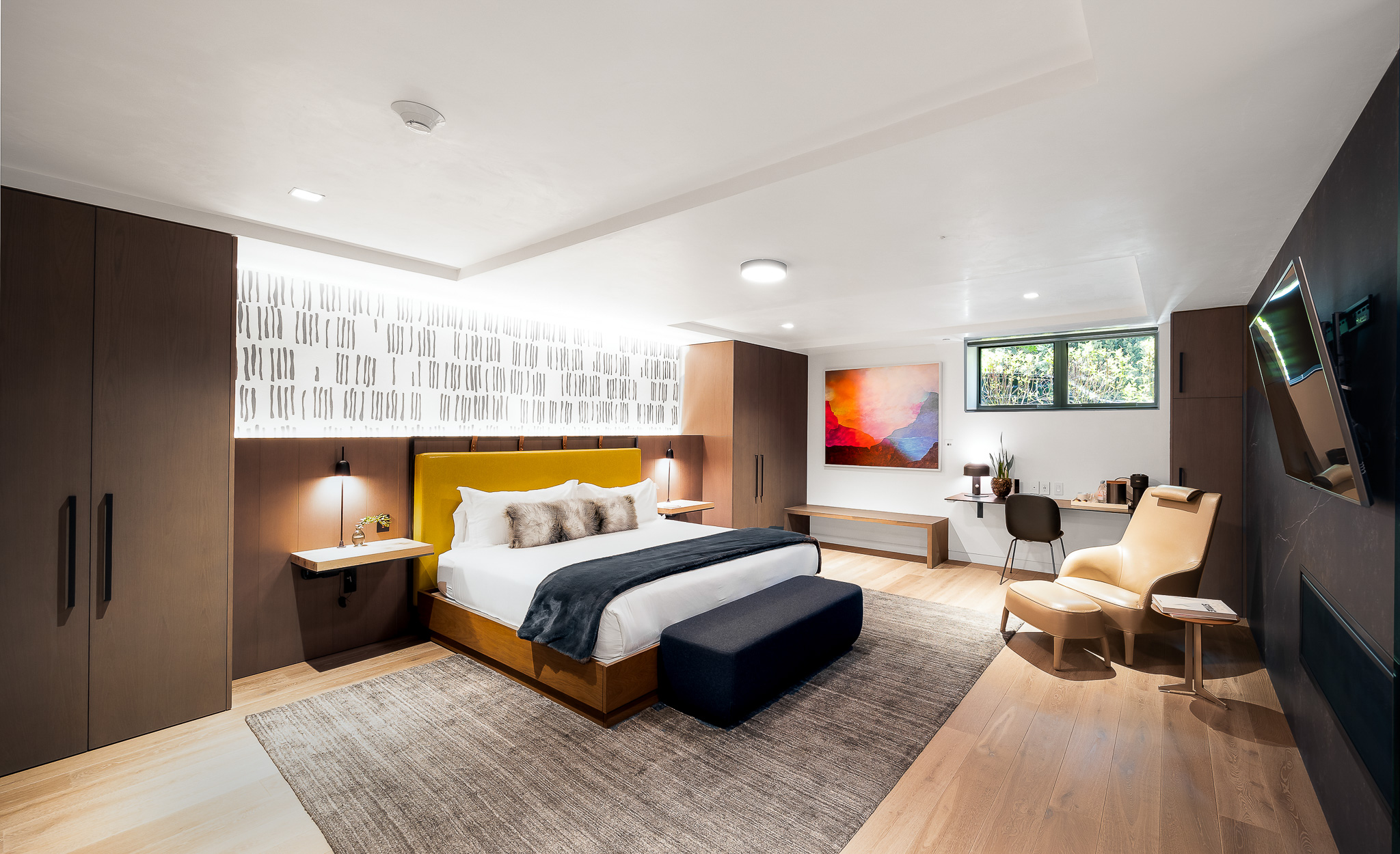 Luxurious bedroom interior with modern furnishings, including a king-size bed, leather chair, and abstract artwork, in a vacation villa rental in Aspen, Colorado.