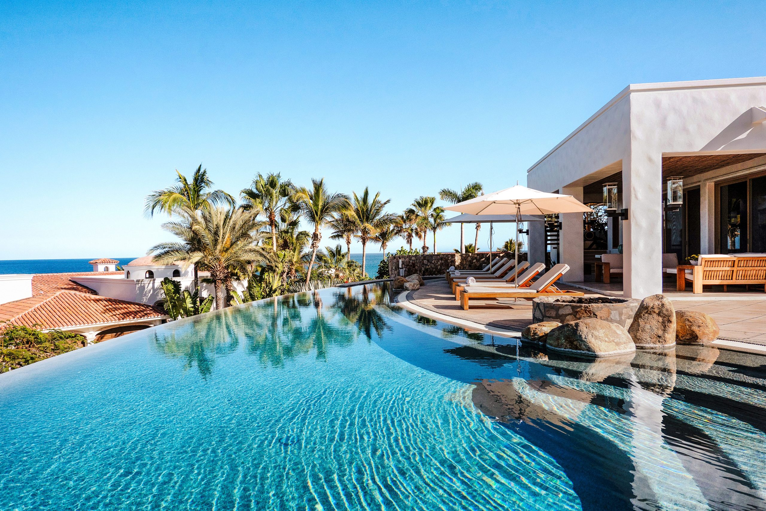 Luxury villa rental with infinity pool, sun loungers, and ocean view in Los Cabos.