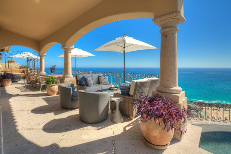 Terrace view of a luxury villa in Los Cabos, Mexico, featuring elegant outdoor seating, large planters, and ocean views.