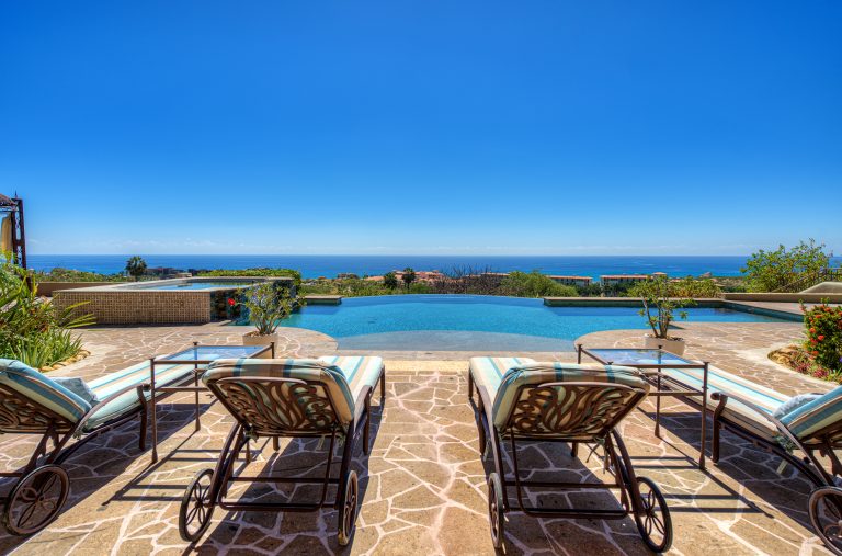 Poolside view with lounge chairs overlooking the ocean at a luxury villa rental in Los Cabos, Mexico.