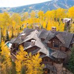 A large luxury villa with a slate roof surrounded by vibrant yellow aspen trees, set against a mountainous backdrop in Beaver Creek, Colorado.