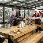 Group of people toasting with champagne in a snowy mountain villa setting.