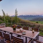Outdoor dining setup on a patio with a panoramic view of mountains and greenery in Aspen, Colorado.