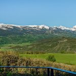Panoramic view of snow-capped mountains and lush green valleys in Aspen, Colorado.
