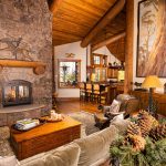 Cozy rustic living room with a stone fireplace, wooden beams, and warm decor.