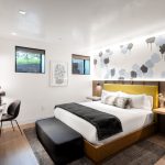 Modern bedroom with a large bed, abstract cloud mural, and minimalistic desk setup in a luxury villa rental.