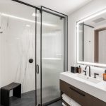 Modern bathroom with a glass shower, illuminated mirror, and sleek vanity.