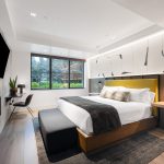 Luxurious bedroom with a modern design, elegant decor, fireplace, and large window overlooking greenery.