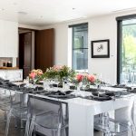 Modern dining area with white table, clear chairs, and floral centerpiece in a luxury villa rental.