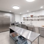 Modern industrial kitchen with stainless steel appliances, metal island, and white subway tile backsplash.