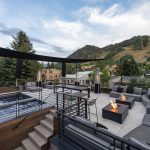 Outdoor seating area with modern fire pits, surrounded by trees and hills in Aspen, Colorado.