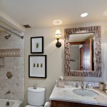Bathroom with marble countertop, framed insect art, and a tiled shower in a luxury villa.