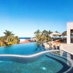 Luxury villa with an infinity pool, surrounded by palm trees and ocean views in Los Cabos.