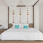 Elegant bedroom with a canopy bed, decorative pillows, and colorful wall accents in a luxury villa rental.