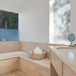 Luxurious bathroom with a marble bathtub, countertop, and a basket of rolled towels.