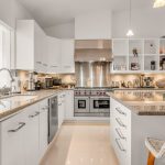 Luxurious modern kitchen with stainless steel appliances, white cabinetry, granite countertops, and island seating.