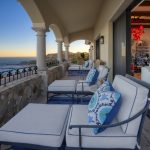 Luxurious villa balcony overlooking the ocean with comfortable seating and a view of the beach.