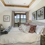 Luxurious bedroom with elegant decor, featuring a large bed with patterned pillows and a view of the mountains through a window.