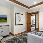Cozy living area with a flat-screen TV, dresser, artwork, and a view into a bedroom.