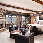 Luxury villa interior with a cozy bedroom, fireplace, and mountain view through large windows.