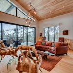 Luxurious villa living room with contemporary furnishings, large windows overlooking snow-covered mountains in Vail, Colorado.