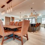 Dining room in a luxury villa with a wooden table, leather chairs, and modern lighting fixtures.