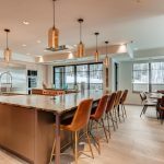 Luxury kitchen with a large island, bar seating, modern appliances, and wood accents, overlooking snowy outdoor scenery.