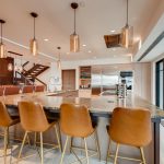Luxurious kitchen in a villa with a large island, leather bar stools, pendant lighting, marble accents, and modern appliances.