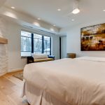 Luxurious bedroom interior with a large bed, fireplace, and window view of snowy mountains.