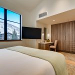 Luxury bedroom with mountain view in Vail, Colorado, featuring a large bed, TV, desk, and modern decor.