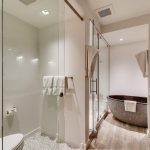 Modern bathroom with glass-enclosed shower, freestanding stone bathtub, and wooden vanity.