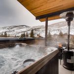 Mountain view from a luxury villa in Vail, Colorado, featuring a hot tub, patio heater, and outdoor seating.