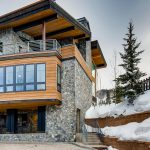 Luxury stone and wood villa in snowy Vail, Colorado, with balconies and large windows.