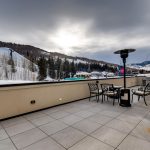 Outdoor patio with seating and heater, overlooking snowy mountains and ski slopes in Vail, Colorado.