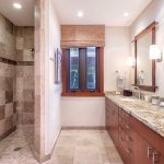 Luxury bathroom with dual sink vanity, granite countertop, large mirror, and walk-in tiled shower.