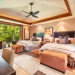 A luxurious bedroom with two beds, modern decor, and an outdoor view of lush greenery.