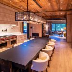 Luxury villa interior with modern dining area and kitchen, featuring a long table, cushioned chairs, and ambient lighting, located in Telluride, Colorado.