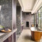 Luxurious bathroom with a copper bathtub, large windows, and marble finishes.
