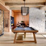 Luxury villa interior with pool table, modern decor, and natural wood and stone accents.