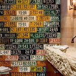 Wall of vintage Colorado license plates in a bathroom with a rustic stone sink.